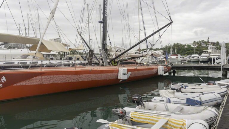 The sides of this Vendee Globe racer are covered in sponsor's names. While the boat looks sleek, it has been at the docks for a while and has a lot of bottom growth which will need to be removed before she races again